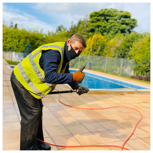 Pressure washing a patio near a swimming pool